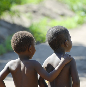 the backs of two african little boys looking forward